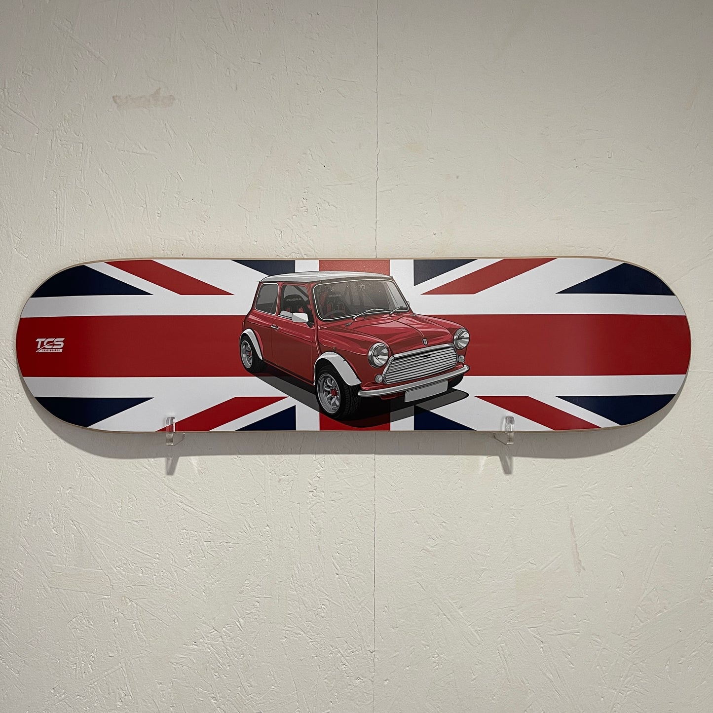 Skateboard deck with a red car and British flag design on a white wall.