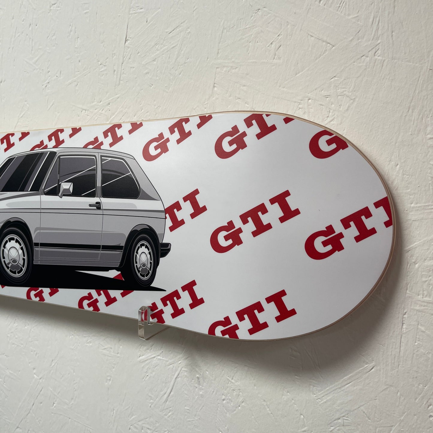 White skateboard with red text and black car design on a light gray background