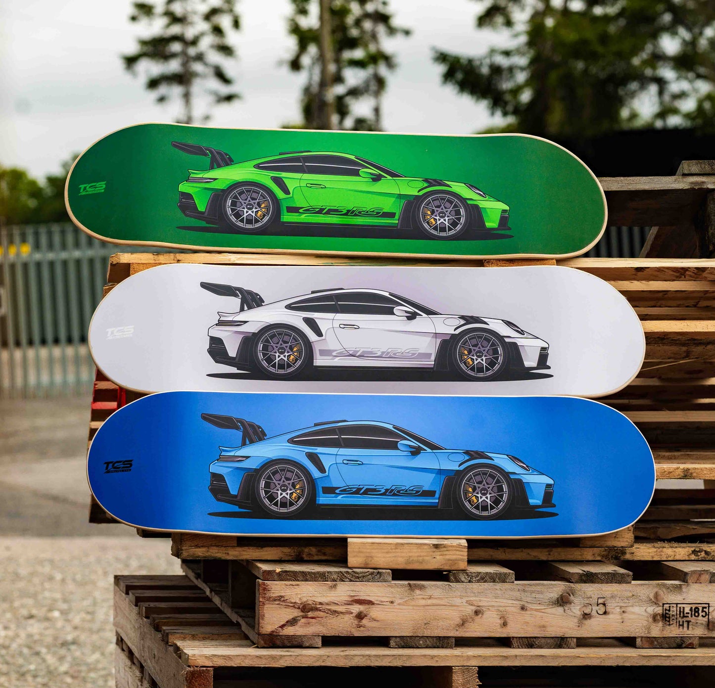 Three skateboard decks with GT3 RS designs stacked on a wooden pallet.