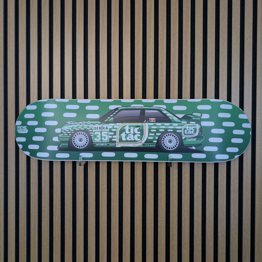 Skateboard deck with car design and 'tic tac' branding on a striped background