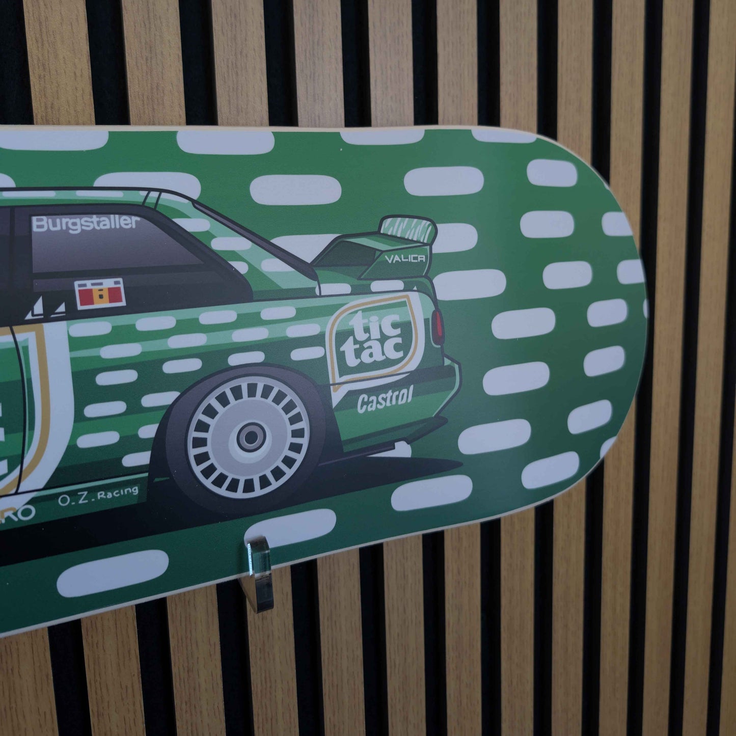 Skateboard deck with green and white design featuring a car on a wooden background