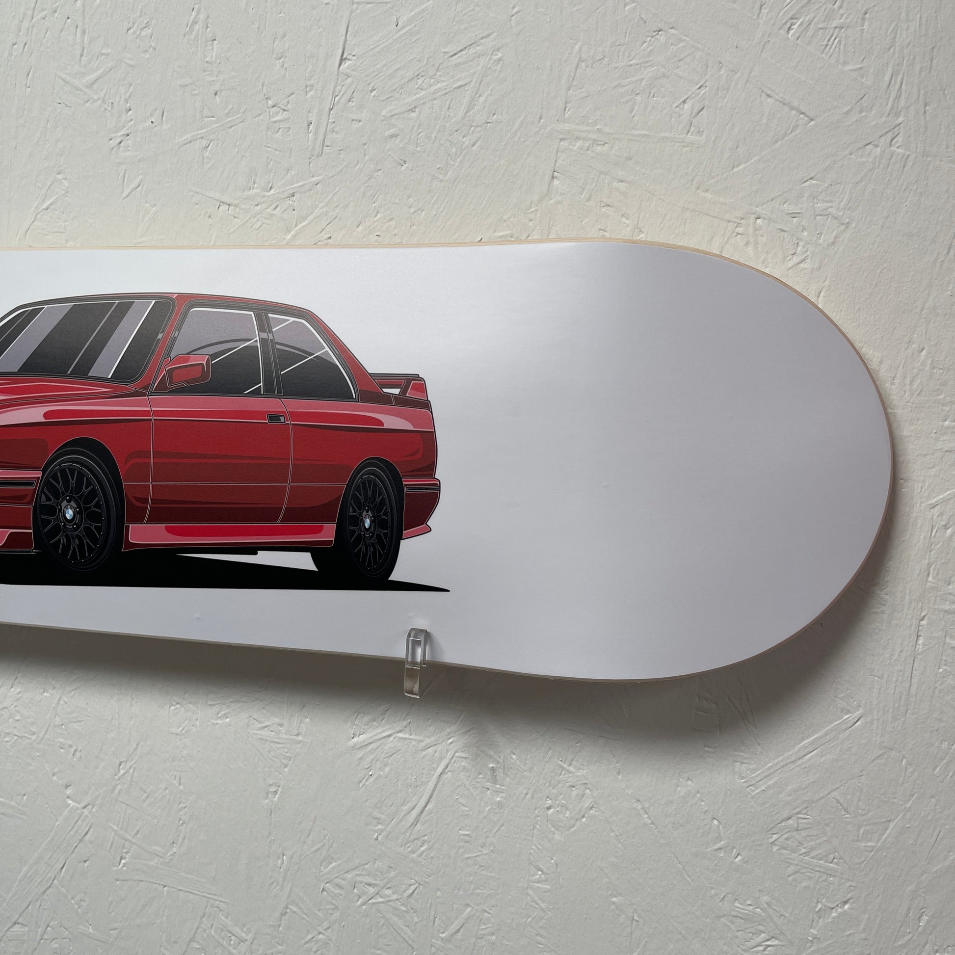 Red car design on a white skateboard deck against a light gray wall.