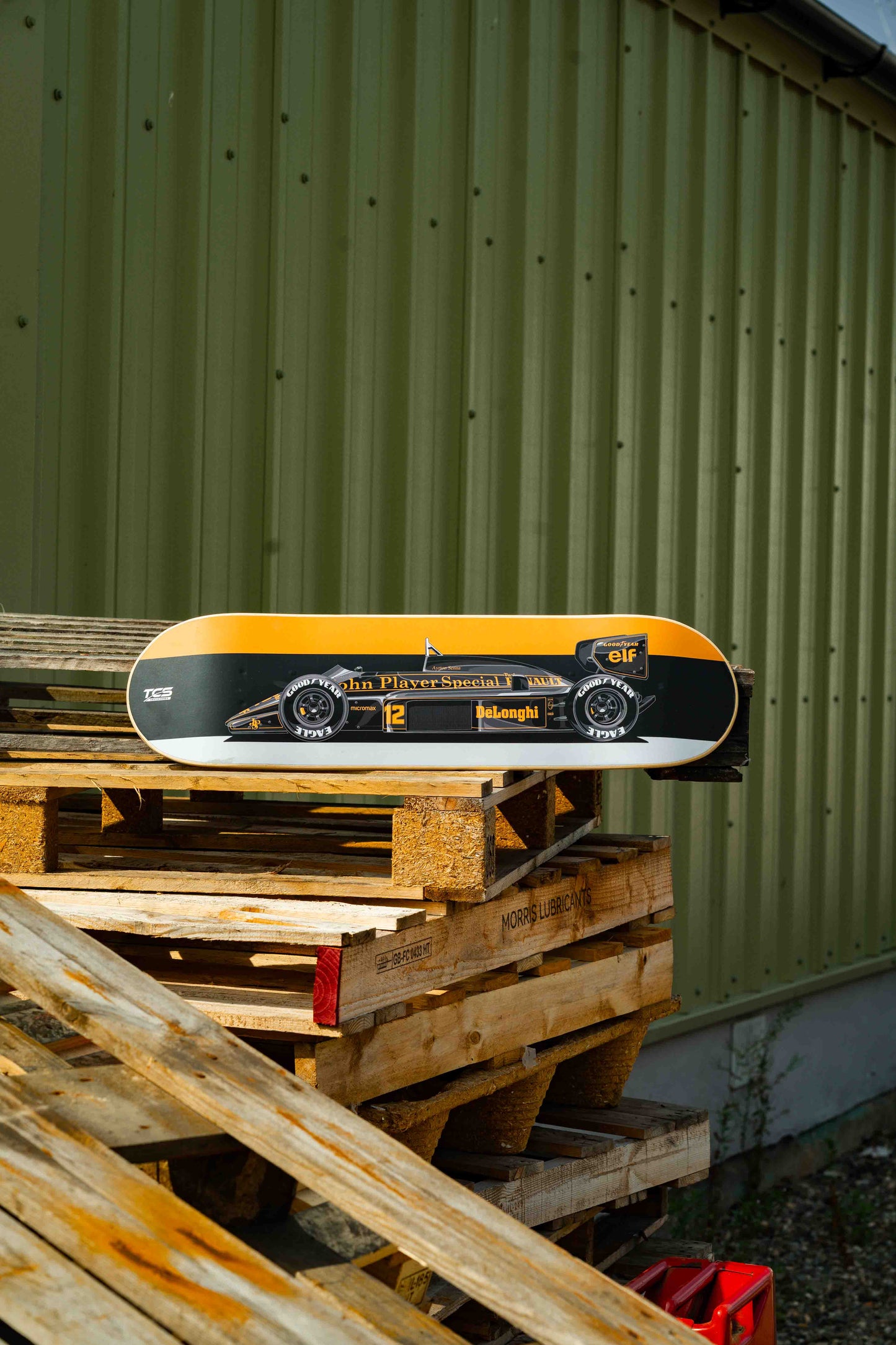 Skateboard with a black and yellow design on wooden pallets against a green wall.