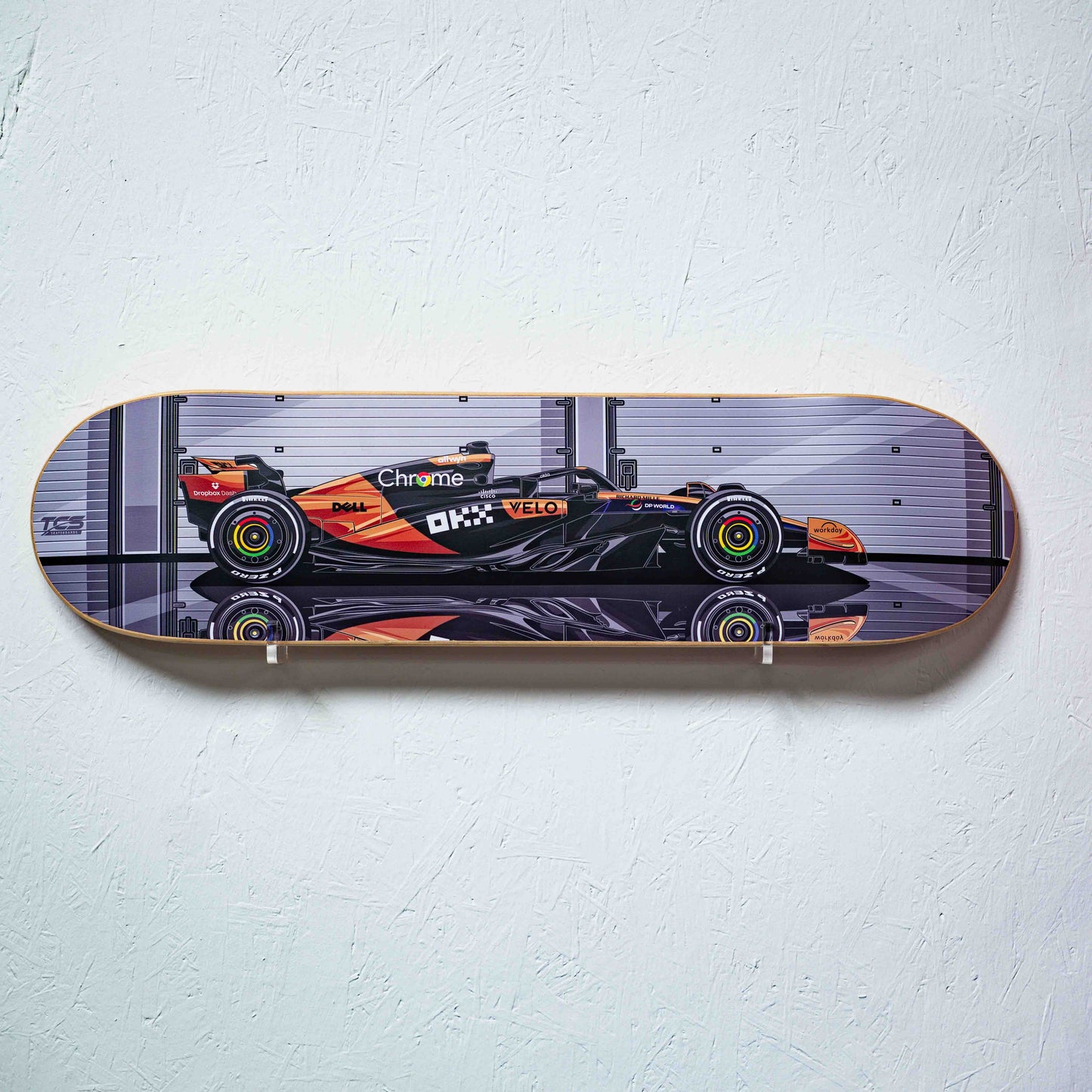 Skateboard deck with a Formula 1 car design on a white wall