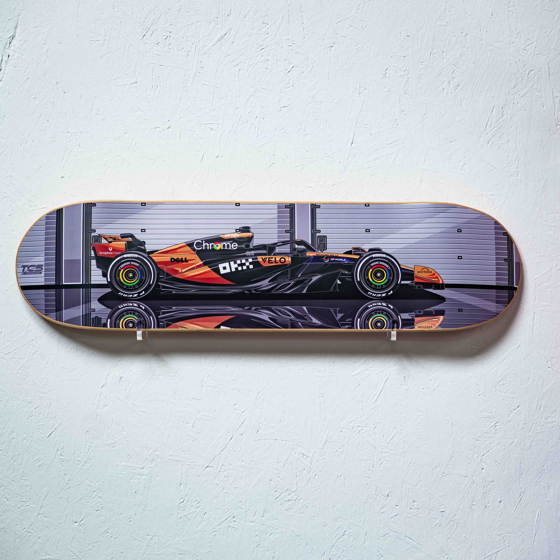 Skateboard deck with a Formula 1 car design on a white wall