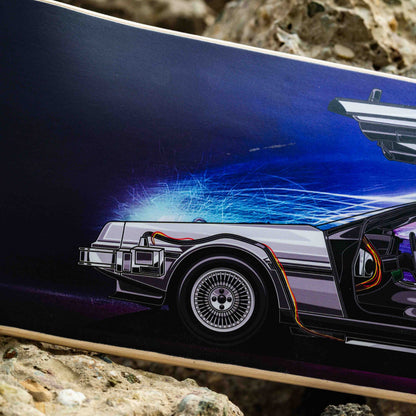 Close-up of a skateboard with a futuristic car design on a rocky surface