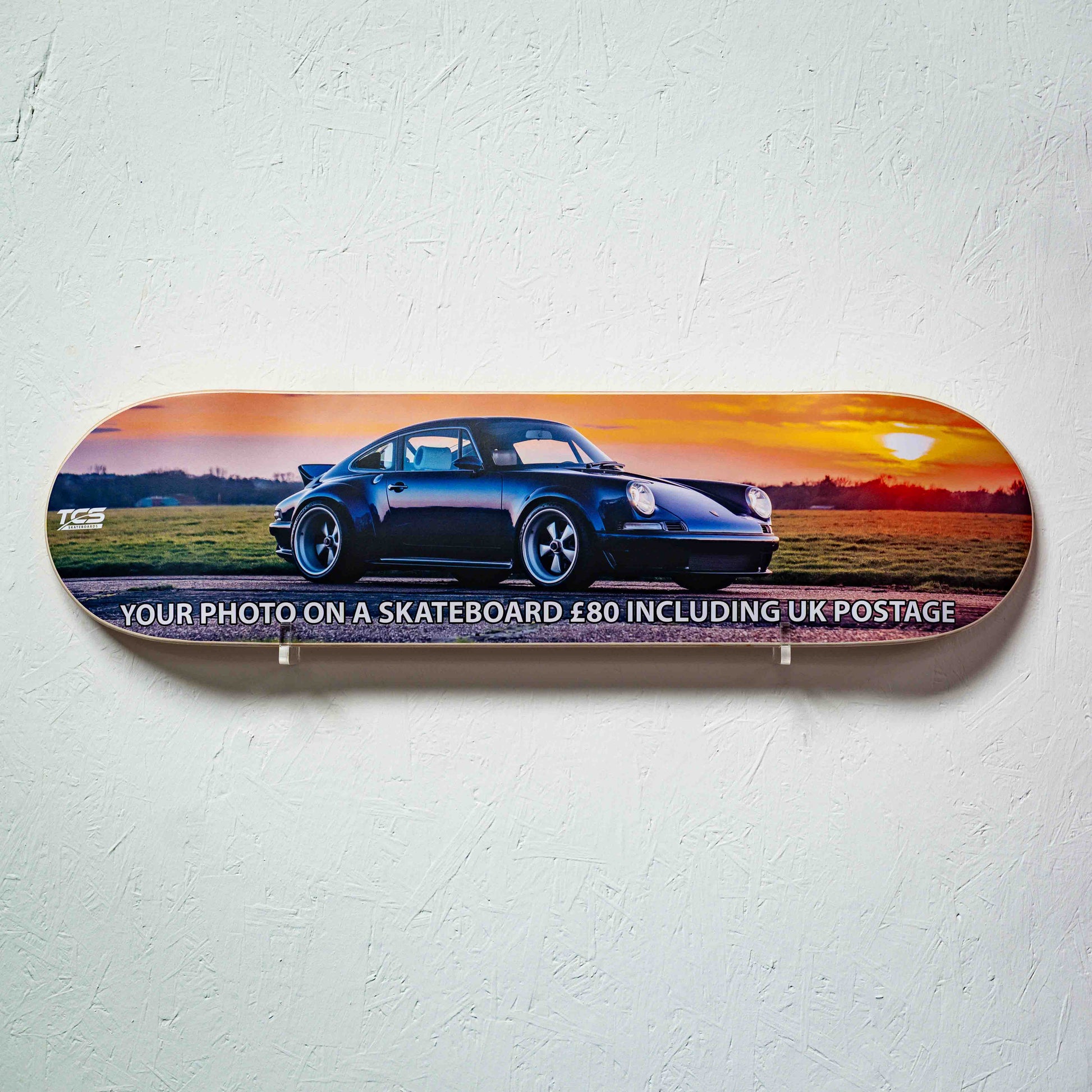 Skateboard with a car design and promotional text on a white wall