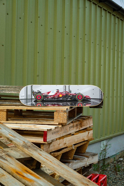 Skateboard with racing car design on a stack of wooden pallets against a green wall.