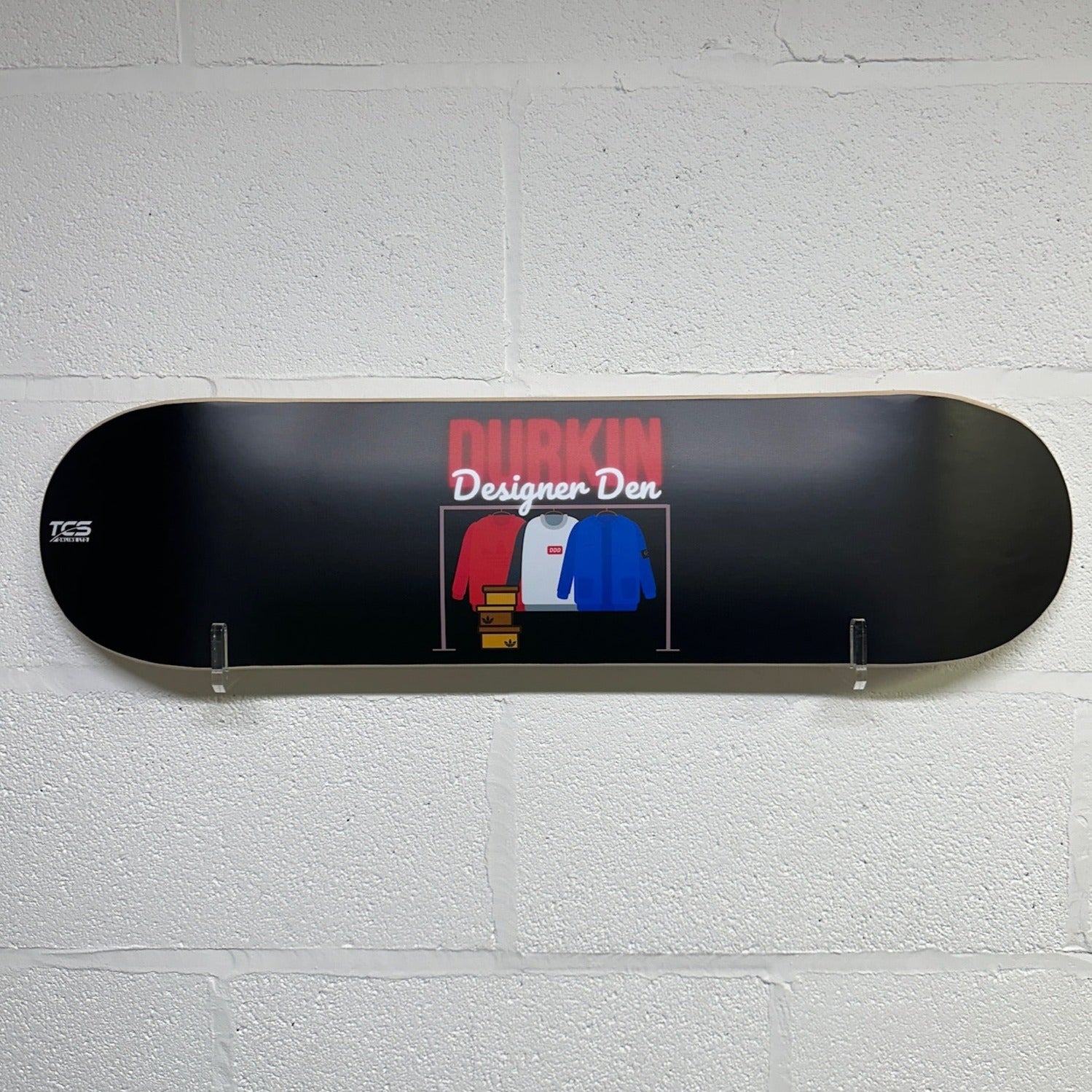A custom logo skateboard wall art mounted on a white wall, featuring a black skateboard deck with a colorful graphic design in the center.