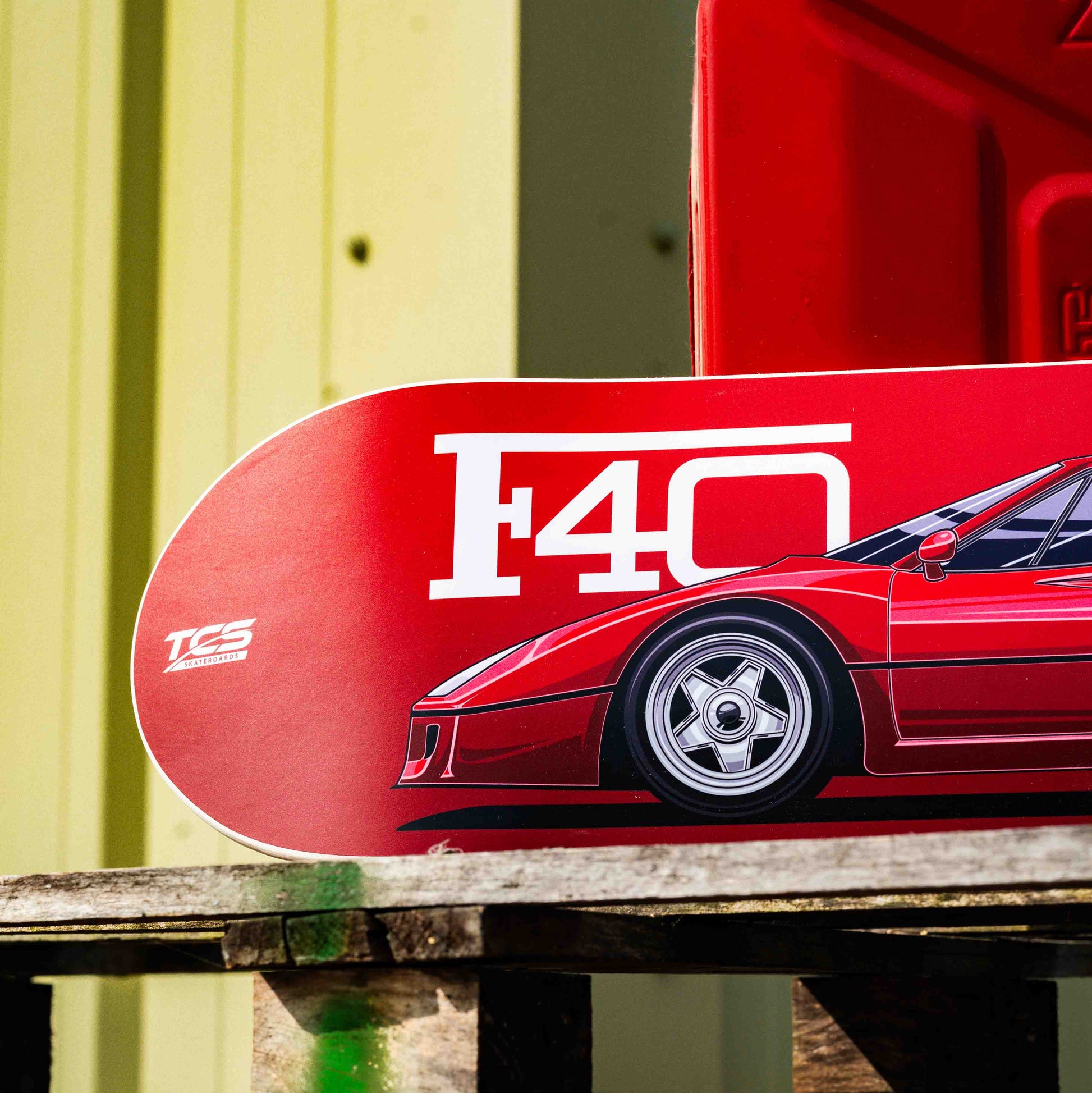 Red Ferrari F40 skateboard deck on a wooden pallet with a yellow wall in the background