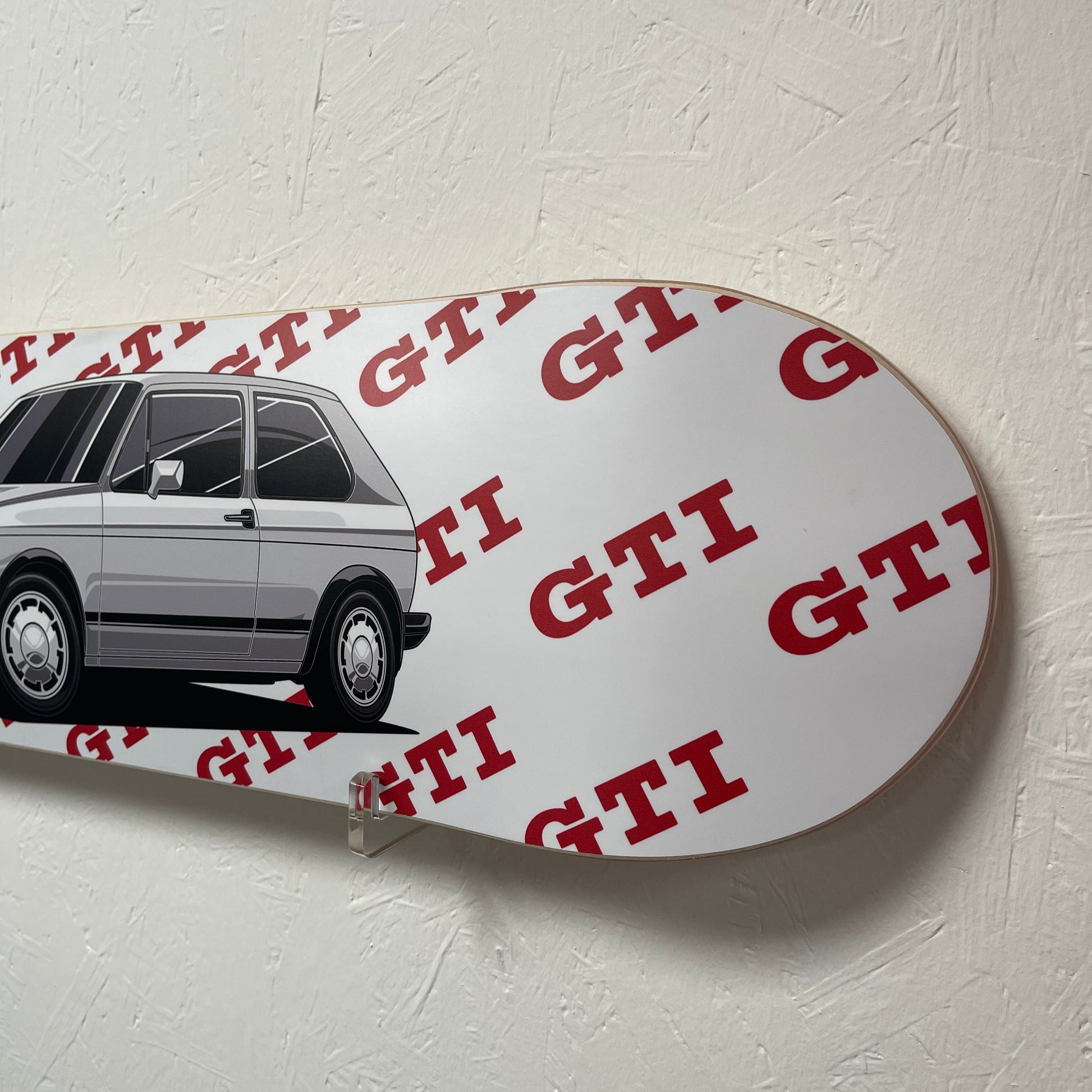 White skateboard with red text and black car design on a light gray background