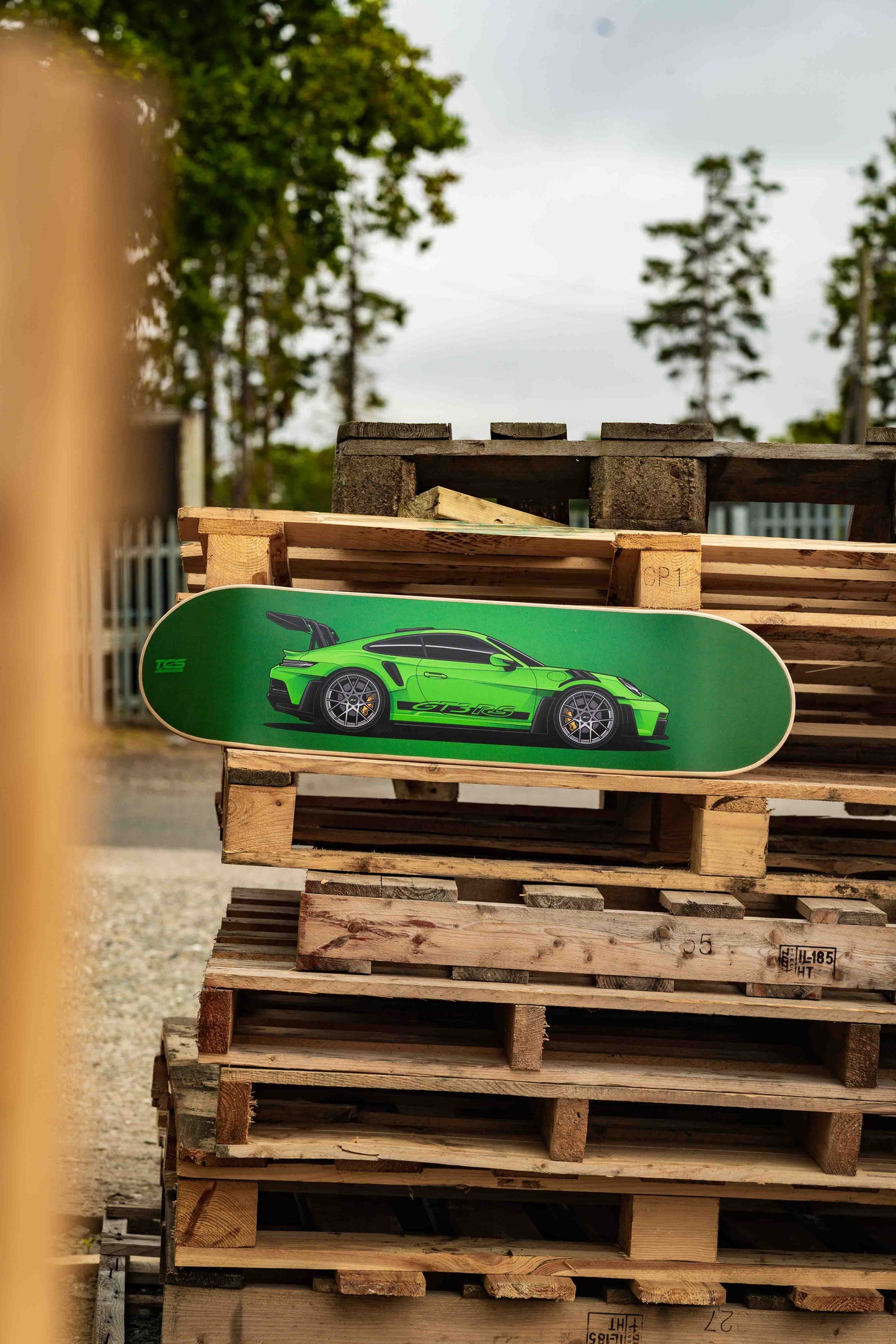 Green skateboard deck with a car design on wooden pallets
