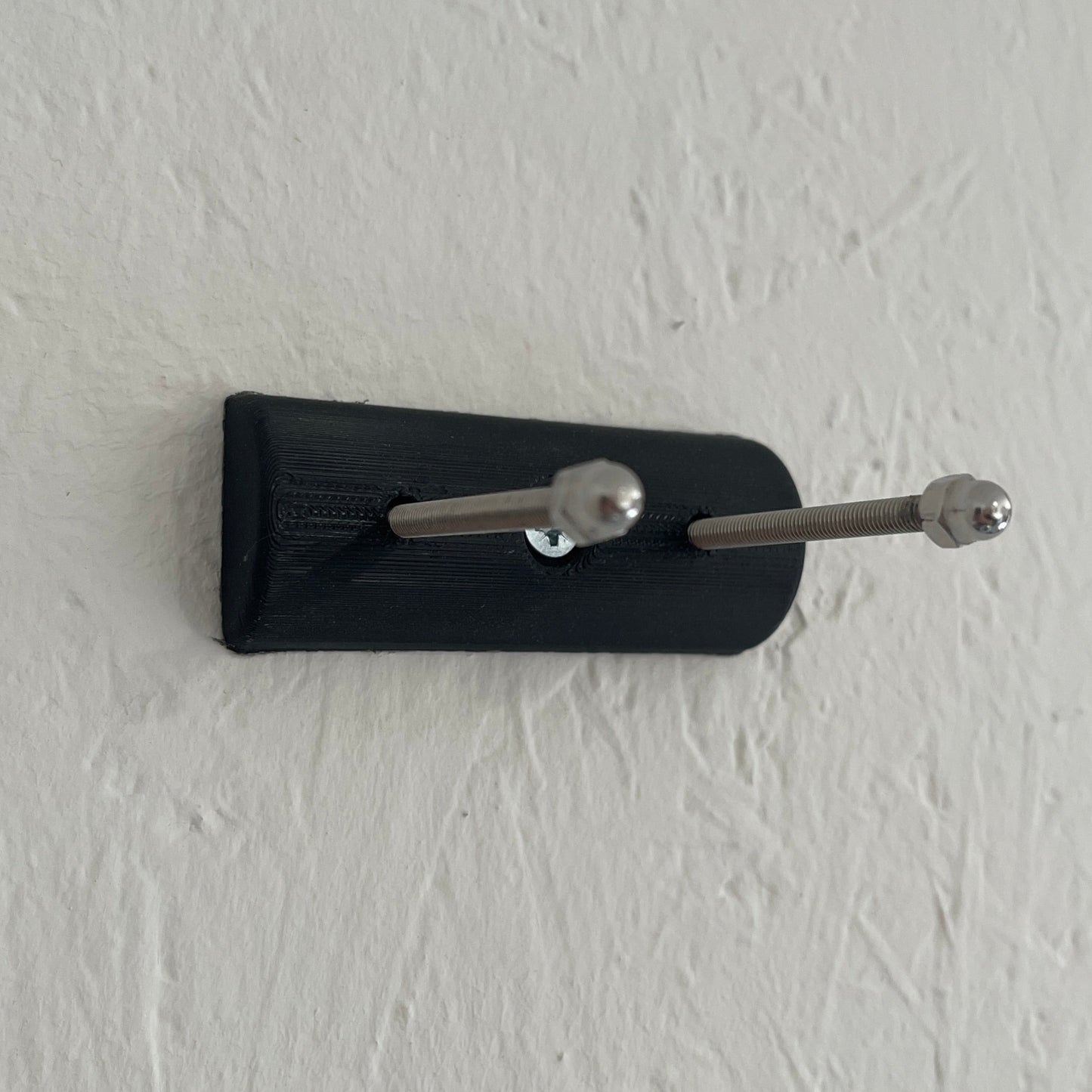 Black key holder with two keys on a white wall
