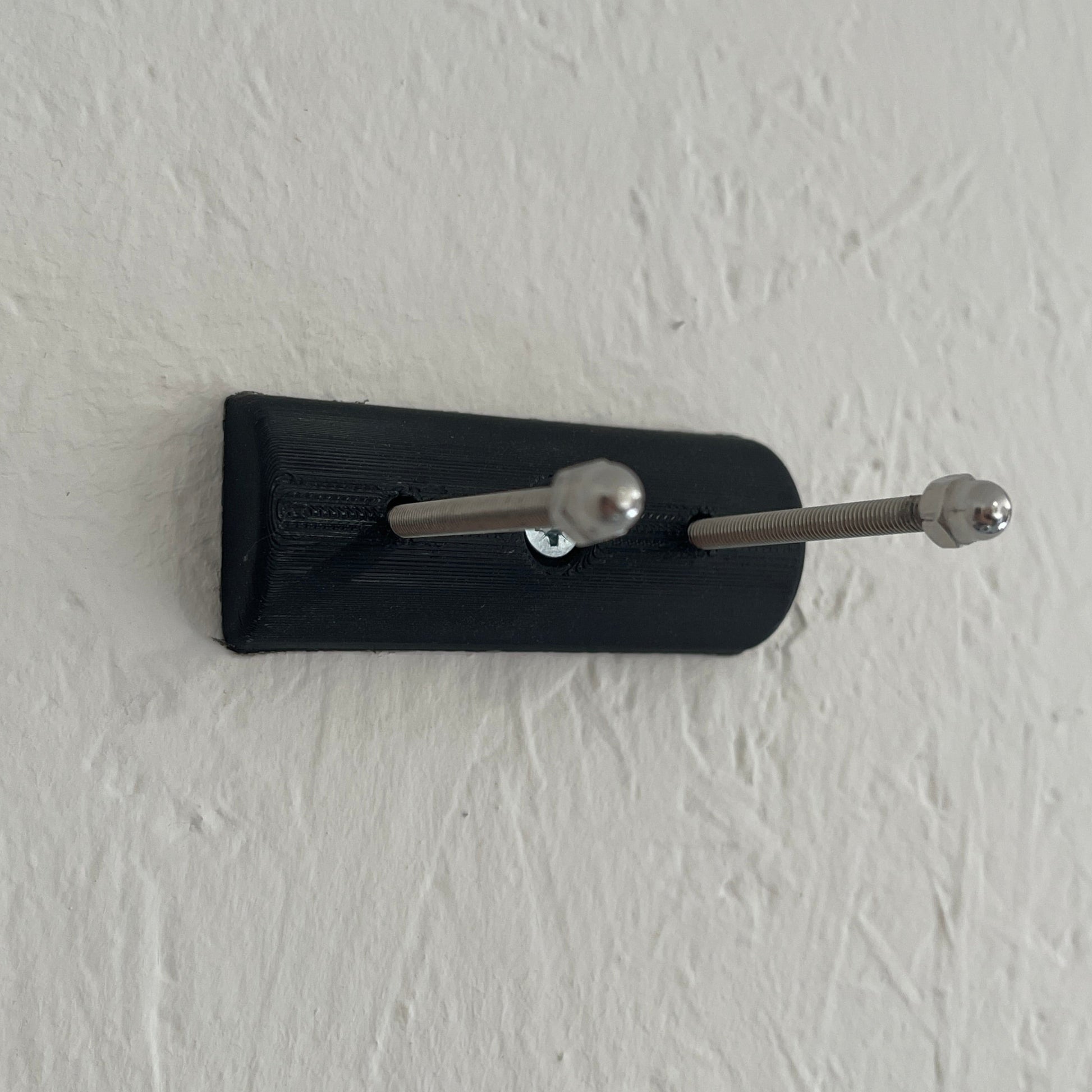 Black key holder with two keys on a white wall