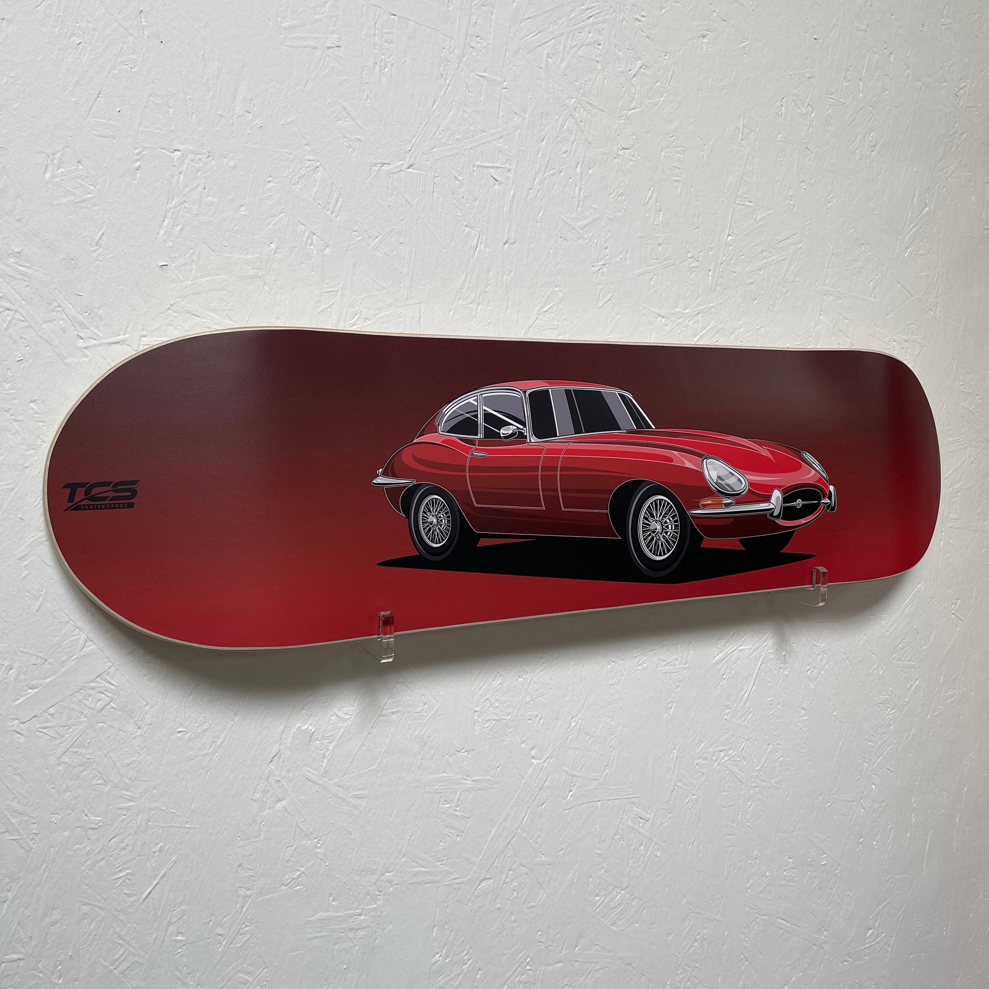 Red skateboard deck with a car design on a white wall