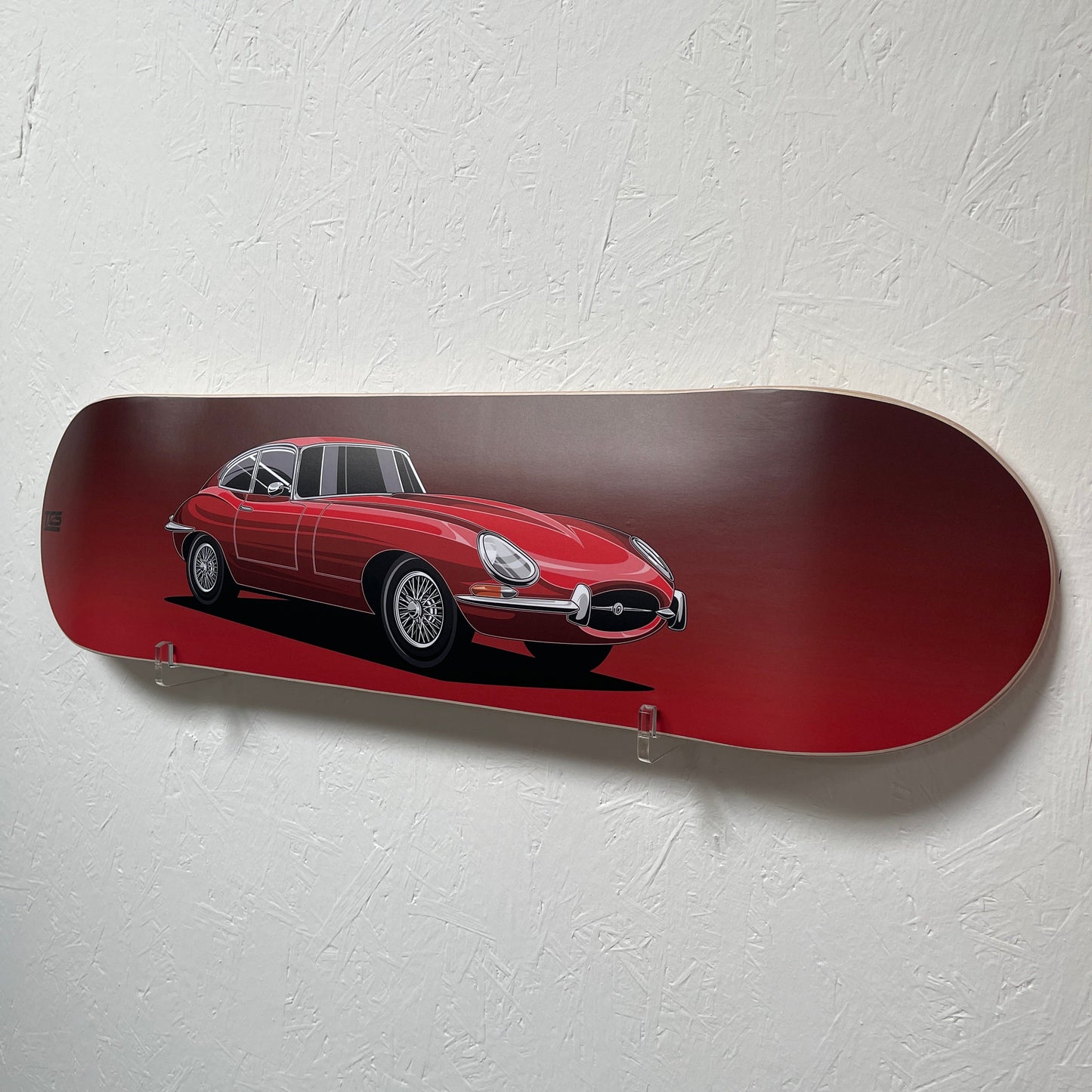 Red skateboard deck with a car design on a white wall