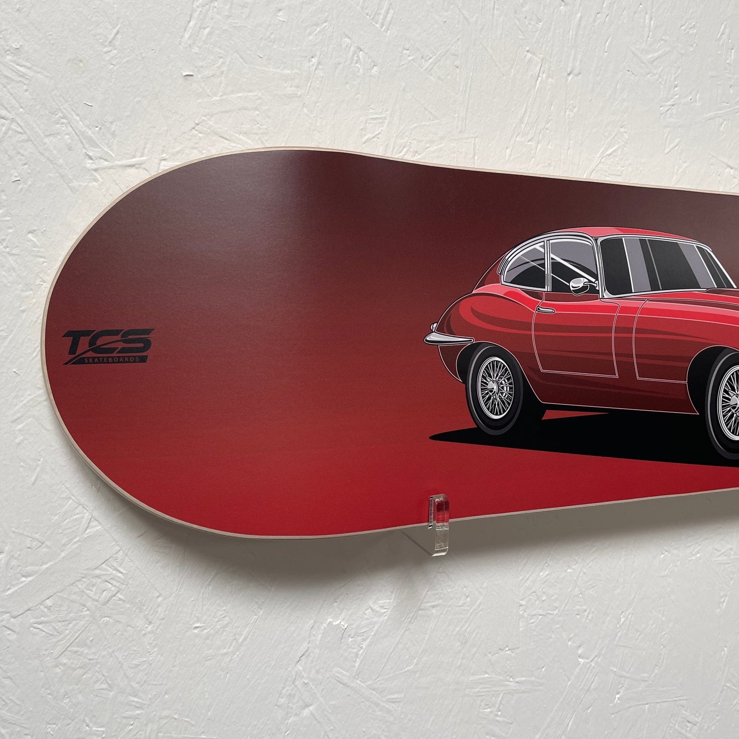 Red skateboard deck with a car design on a white background