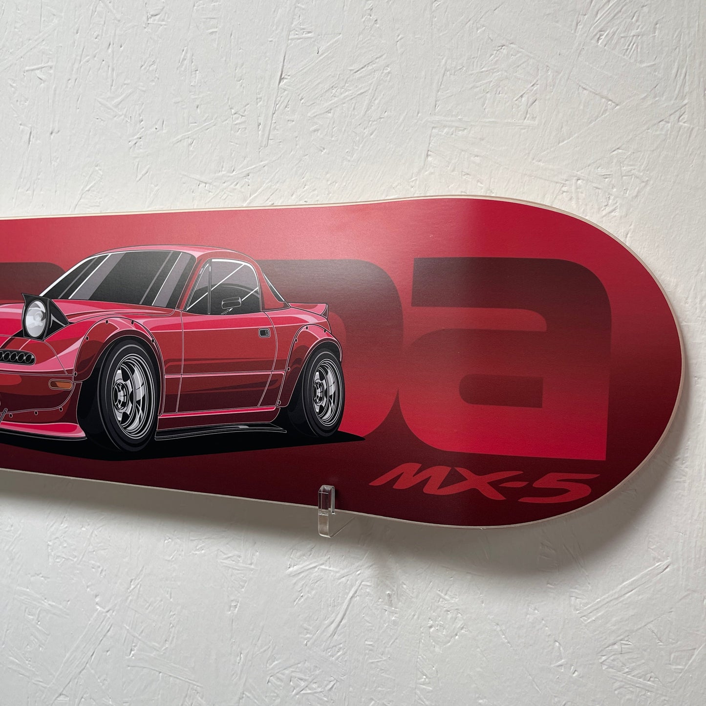 Red skateboard deck with car design and 'MAZDA MX5' logo on a white background