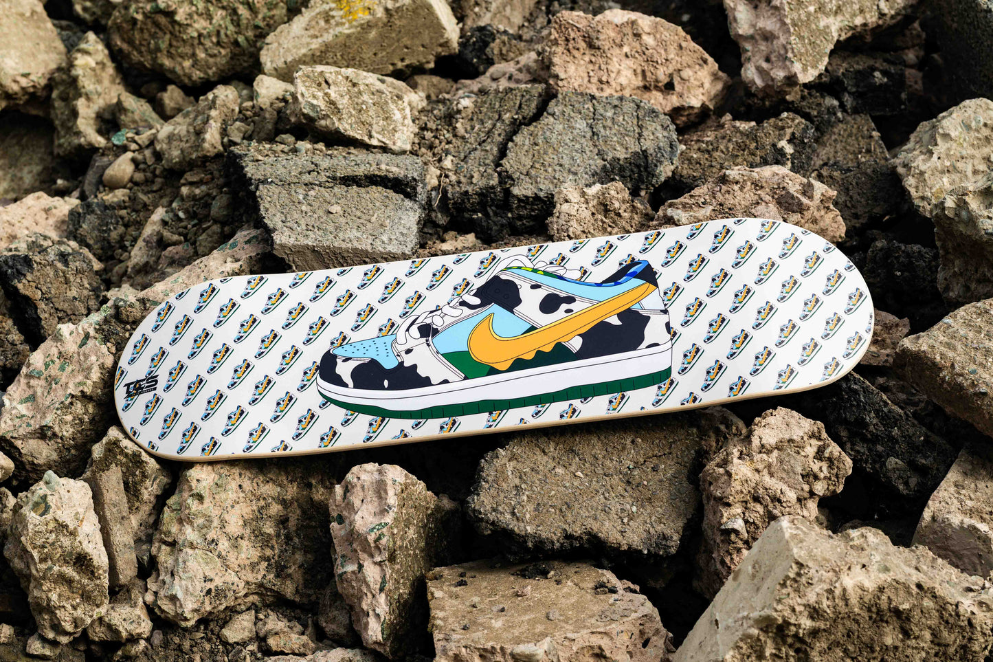 Skateboard deck with cow print design on a rocky surface