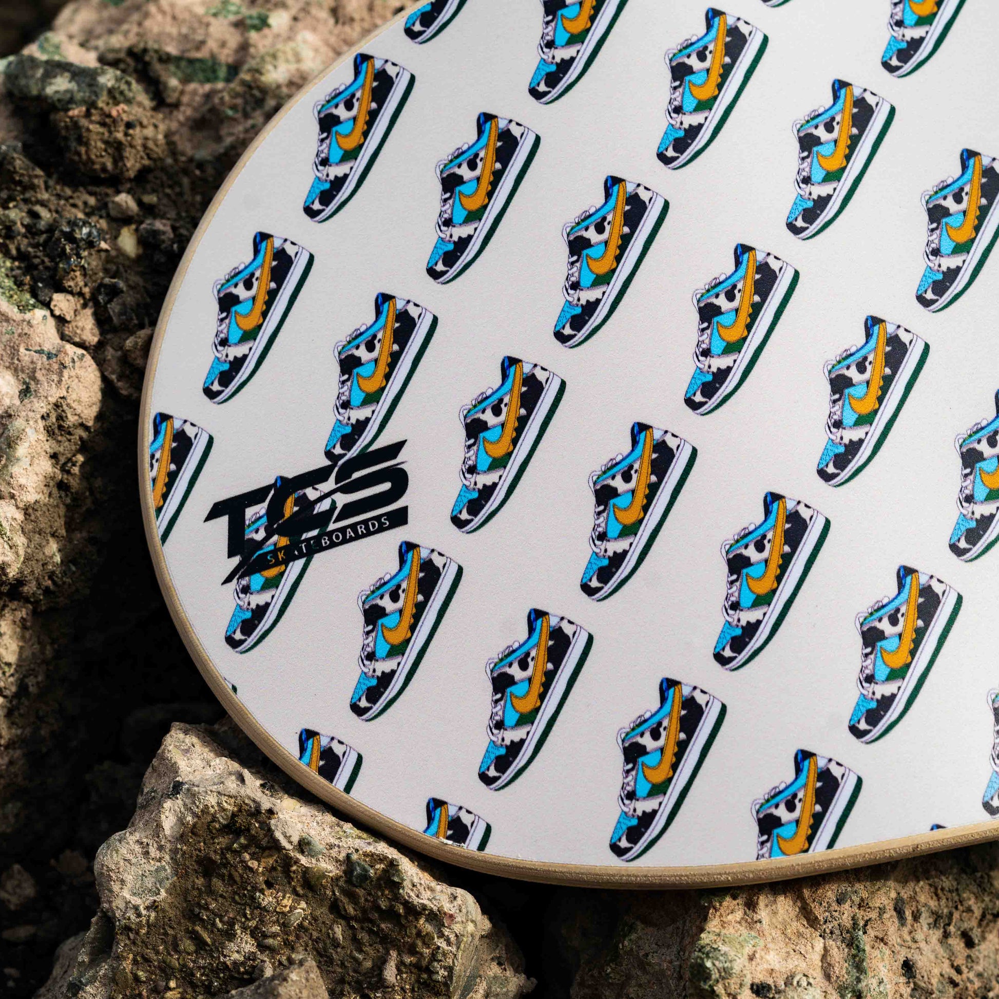 Patterned skateboard on a rock with visible branding