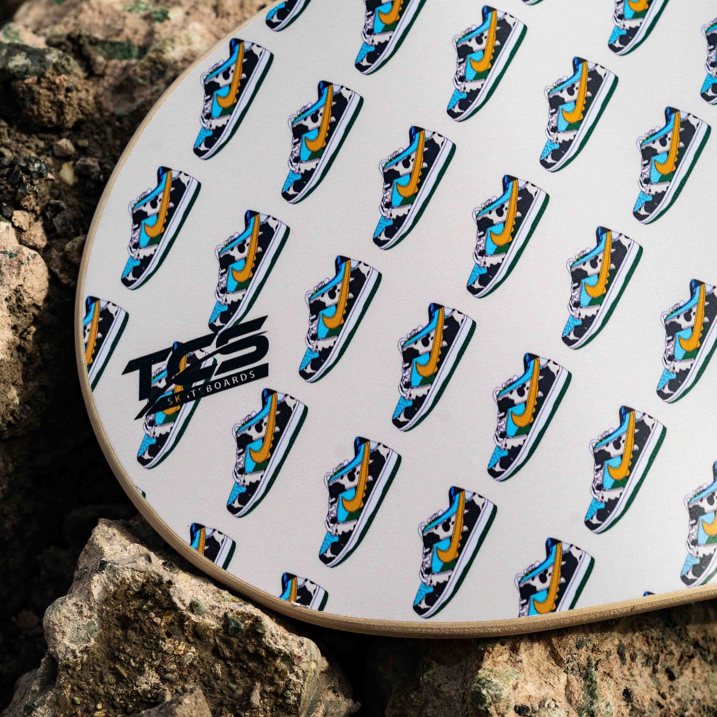 Patterned skateboard on a rock with visible branding