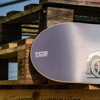 Two skateboard decks with TCS branding and car graphics on a wooden pallet.