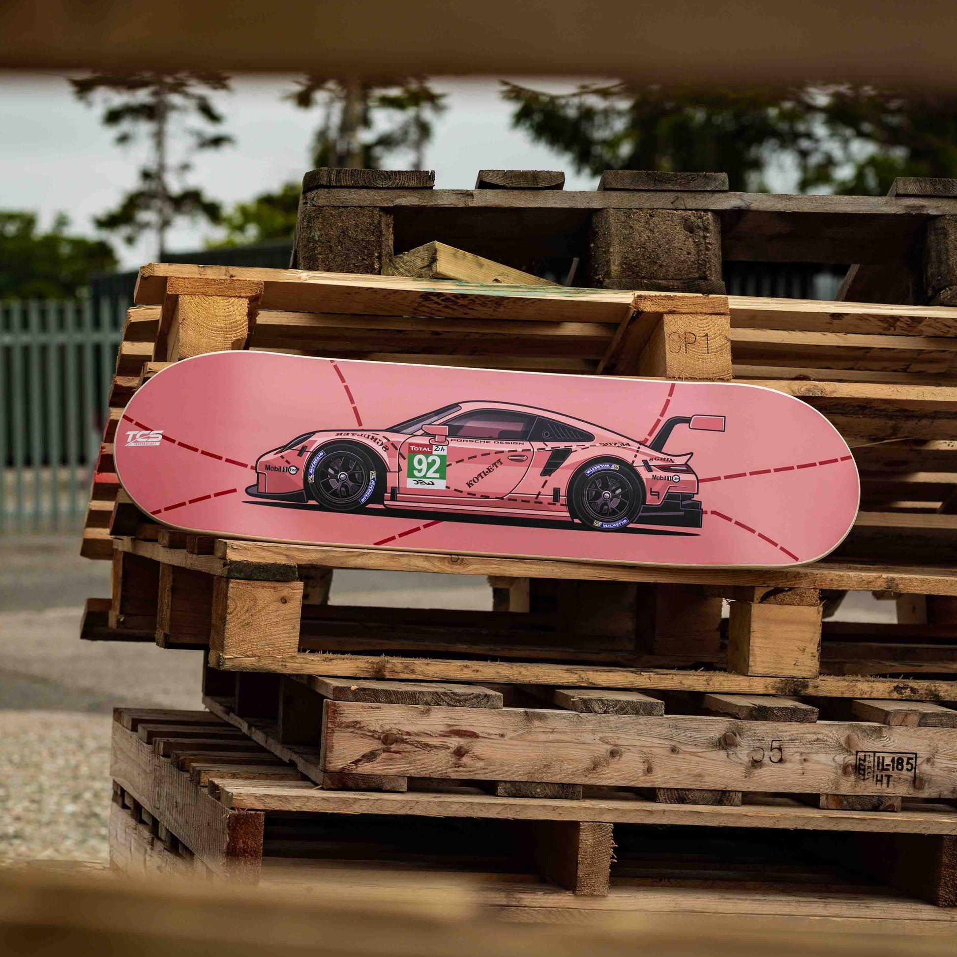 Pink skateboard with a car design on a wooden pallet