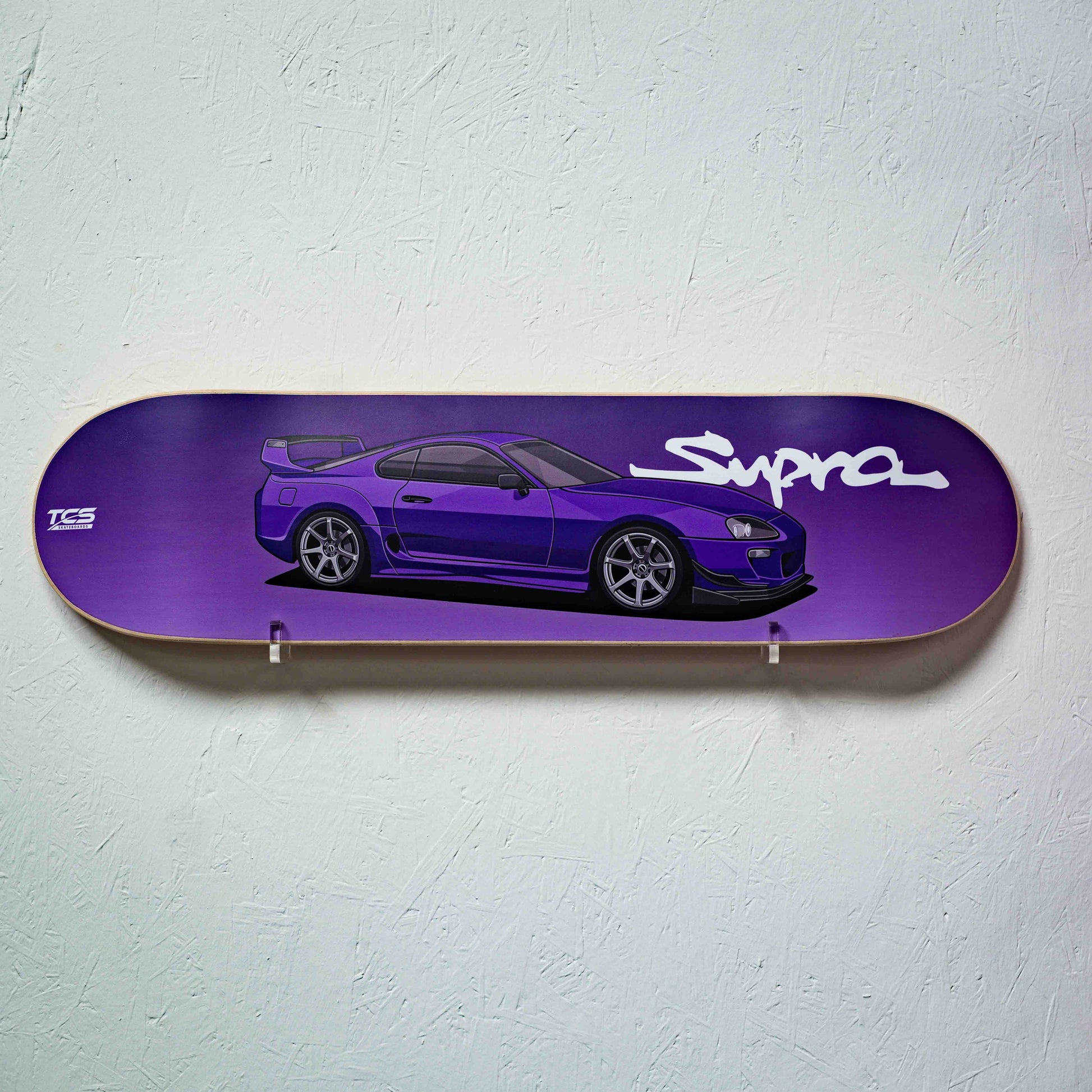 Purple skateboard deck with a car illustration and 'Supra' branding on a light gray background