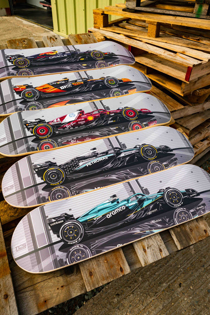 Five skateboard decks with Formula 1 car designs on a wooden pallet.