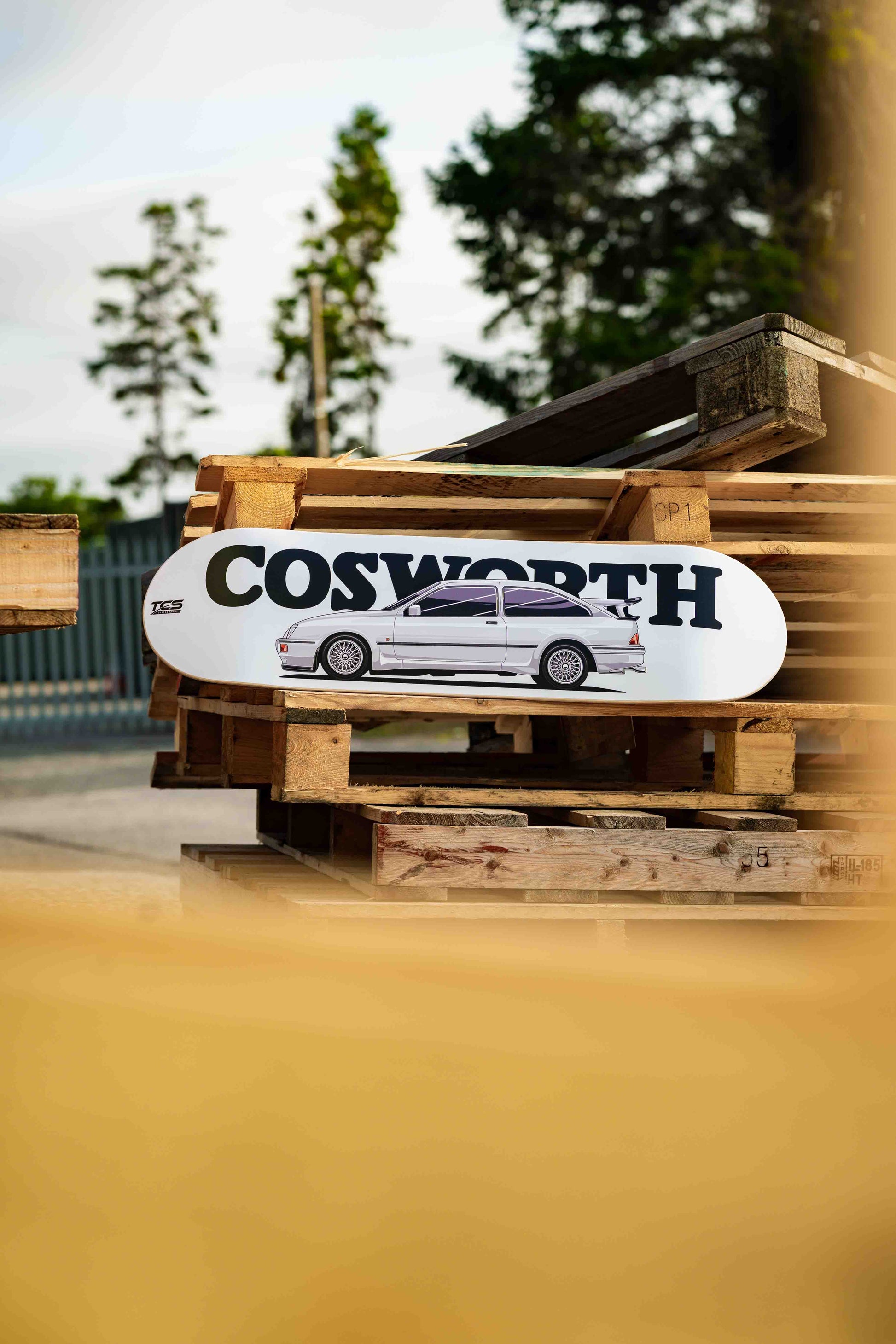 Skateboard with 'Cosworth' logo on a wooden pallet outdoors