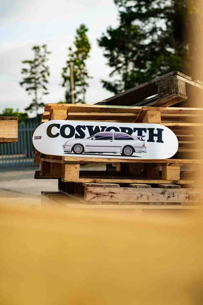 Skateboard with 'Cosworth' logo on a wooden pallet outdoors