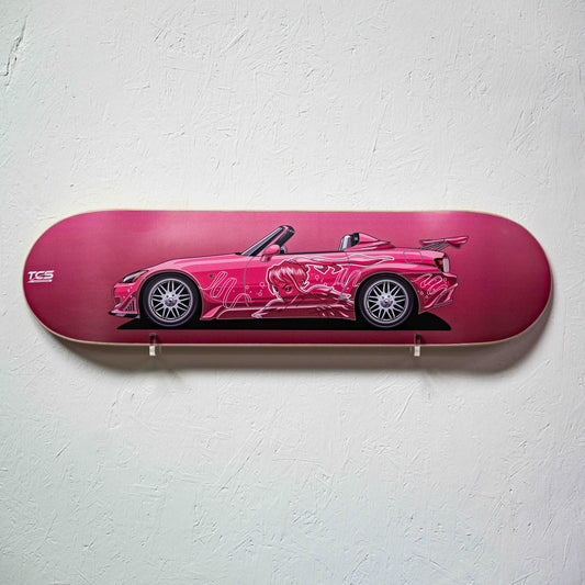 Skateboard deck with a pink car design on a white wall