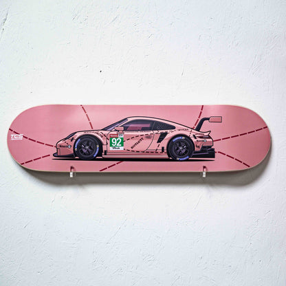 Skateboard deck with a racing car design on a pink background