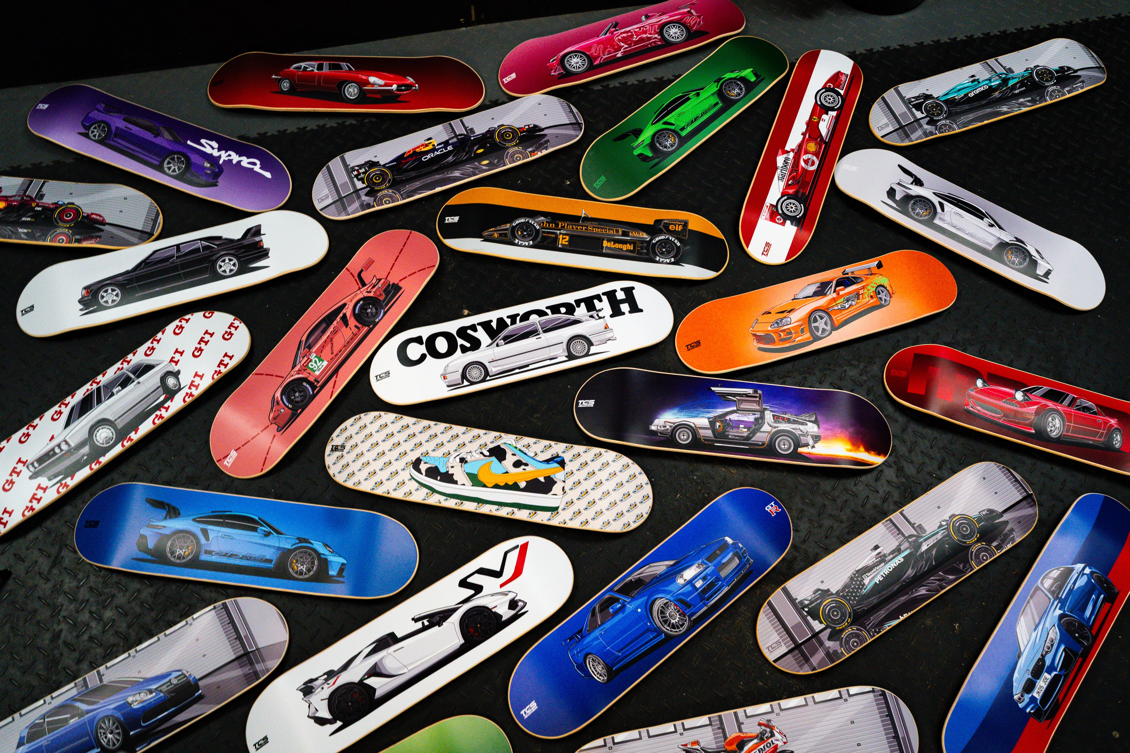 Collection of skateboard decks with car graphics on a dark surface