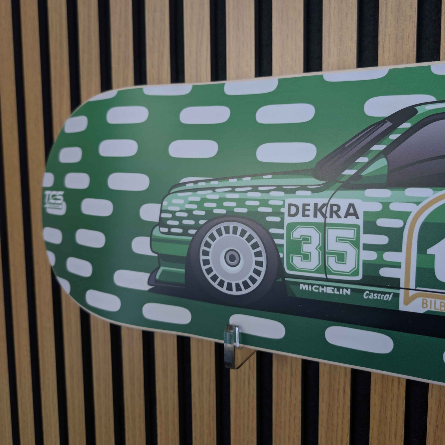 Green skateboard deck with car design and branding against a striped background