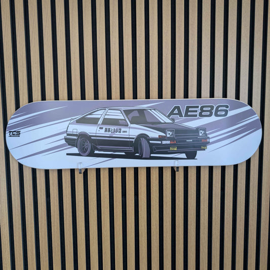 Skateboard deck with a car design and 'AE86' text on a striped background