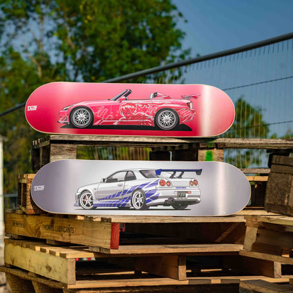Two skateboard decks stacked on a wooden pallet with a scenic background
