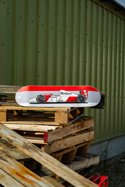 Red and white skateboard deck on wooden pallets with a green corrugated metal background