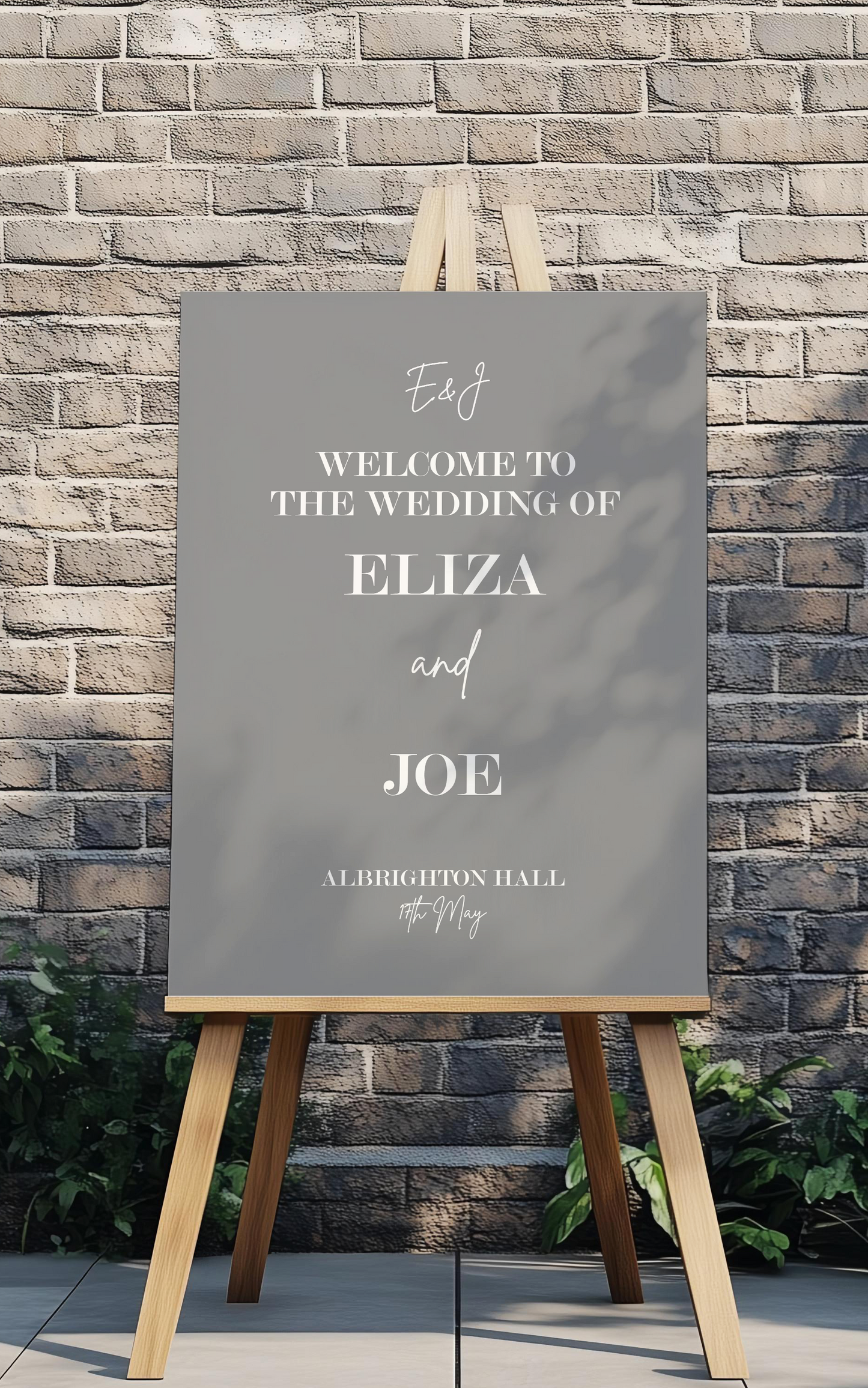 Wedding welcome sign on an easel against a brick wall